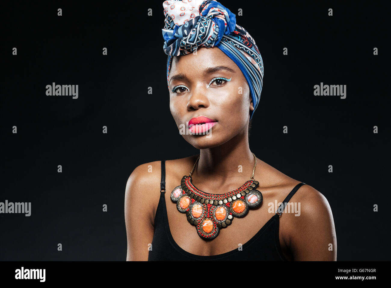 Portrait of a young afro american woman wearing a blue headscarf isolated on the black background Stock Photo
