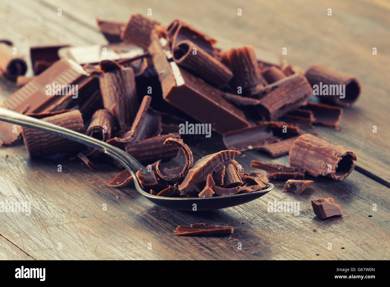 Broken dark chocolate and chocolate shavings on a wooden table Stock Photo