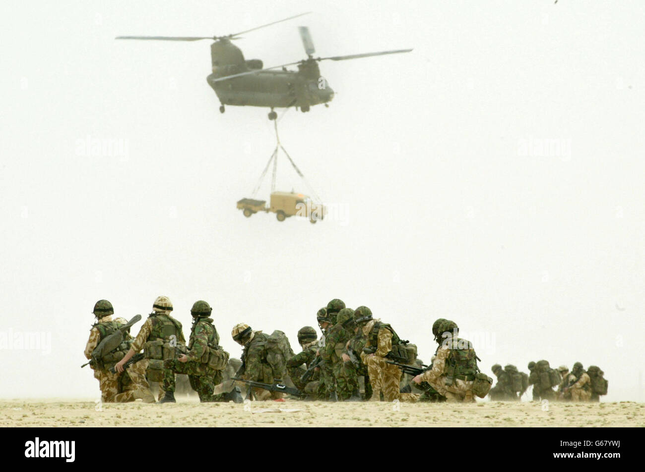 British soldiers of the 51st Sqn Royal Air Force regiment observe a Chinook of the RAF joint helicopter force as it lifts a Land Rover vehicle and its trailer during a practice air assault operation design to capture an enemy airfield, in the desert outside Kuwait City. 07/04/2004: A 'massively botched' procurement has left the RAF with eight Chinook helicopters worth 259 million, which it cannot use, it was revealed Wednesday 7 April 2004. Concerns about cockpit software mean the craft cannot be flown in cloudy weather, said a report by Westminster spending watchdog the National Audit Stock Photo