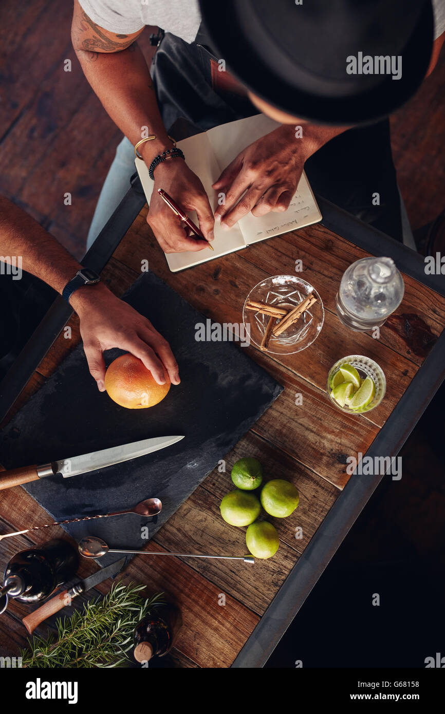 Two bartenders experimenting with creating cocktails and taking down notes. Top view of bar counter with ingredients and accesso Stock Photo