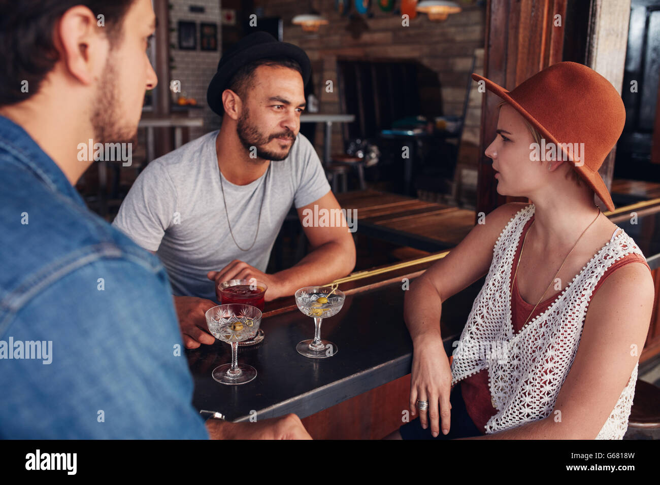 Group of young friends sitting and talking at a cafe. Young men and women meeting in a coffee shop and discussing. Stock Photo