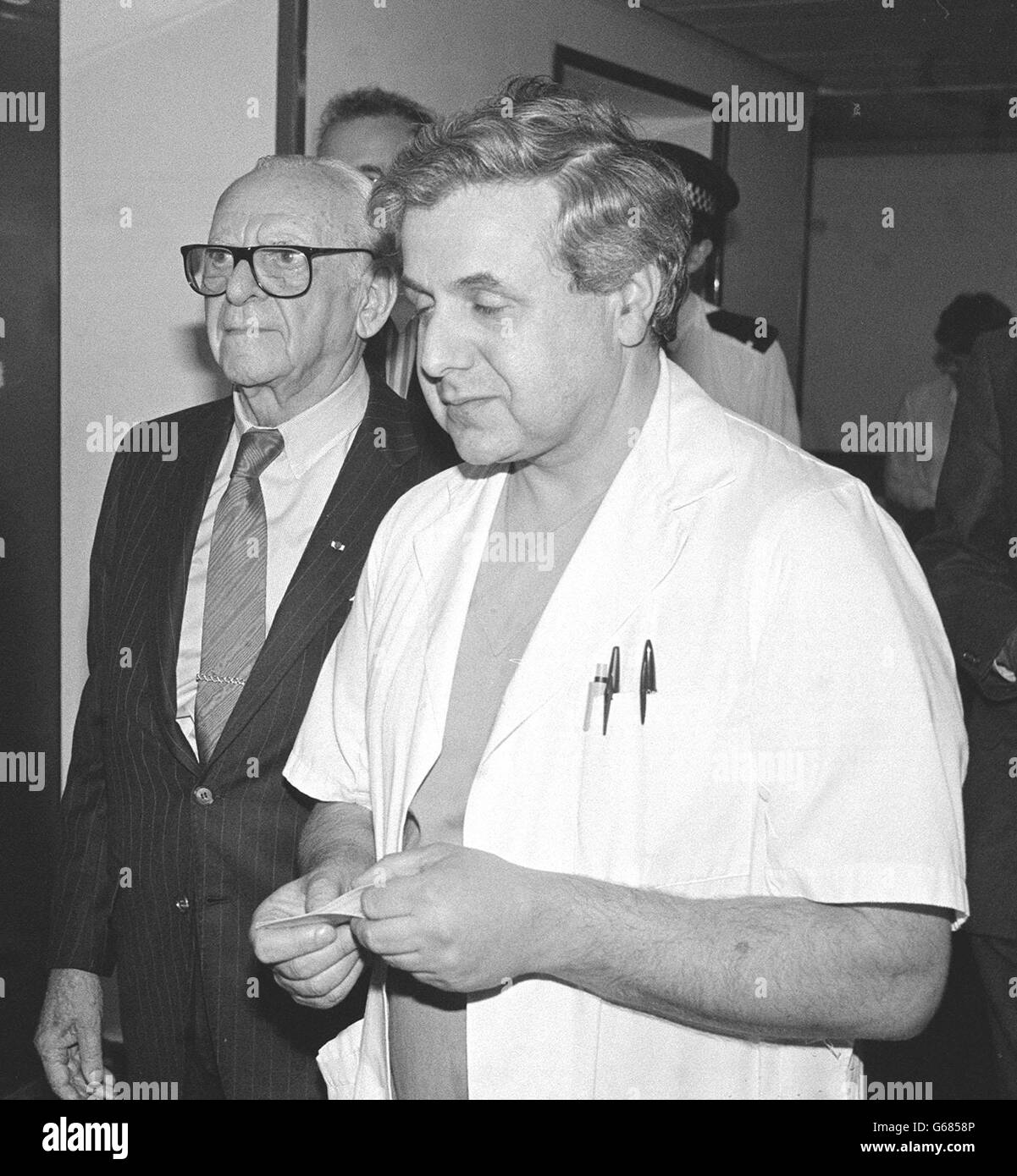Dr Armand Hammer, 90-year-old chairman of Los Angeles-based Occidental Petroleum (glasses) is accompanied by Graham Page, Aberdeen Royal Infirmary's accident and emergency department consultant during his visit to casualties of the North Sea oil platform, Piper Alpha. Dr Hammer, whose company operated the doomed offshore platform, flew into Aberdeen. Stock Photo