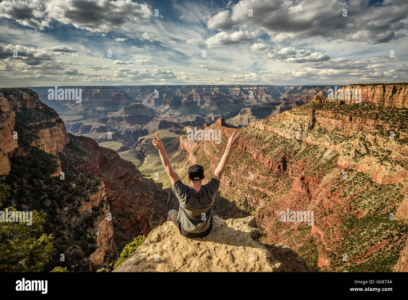 Grand Canyon and a happy hiker on the rim with arms raised up. Winner, success and achievement  concept in nature. Stock Photo