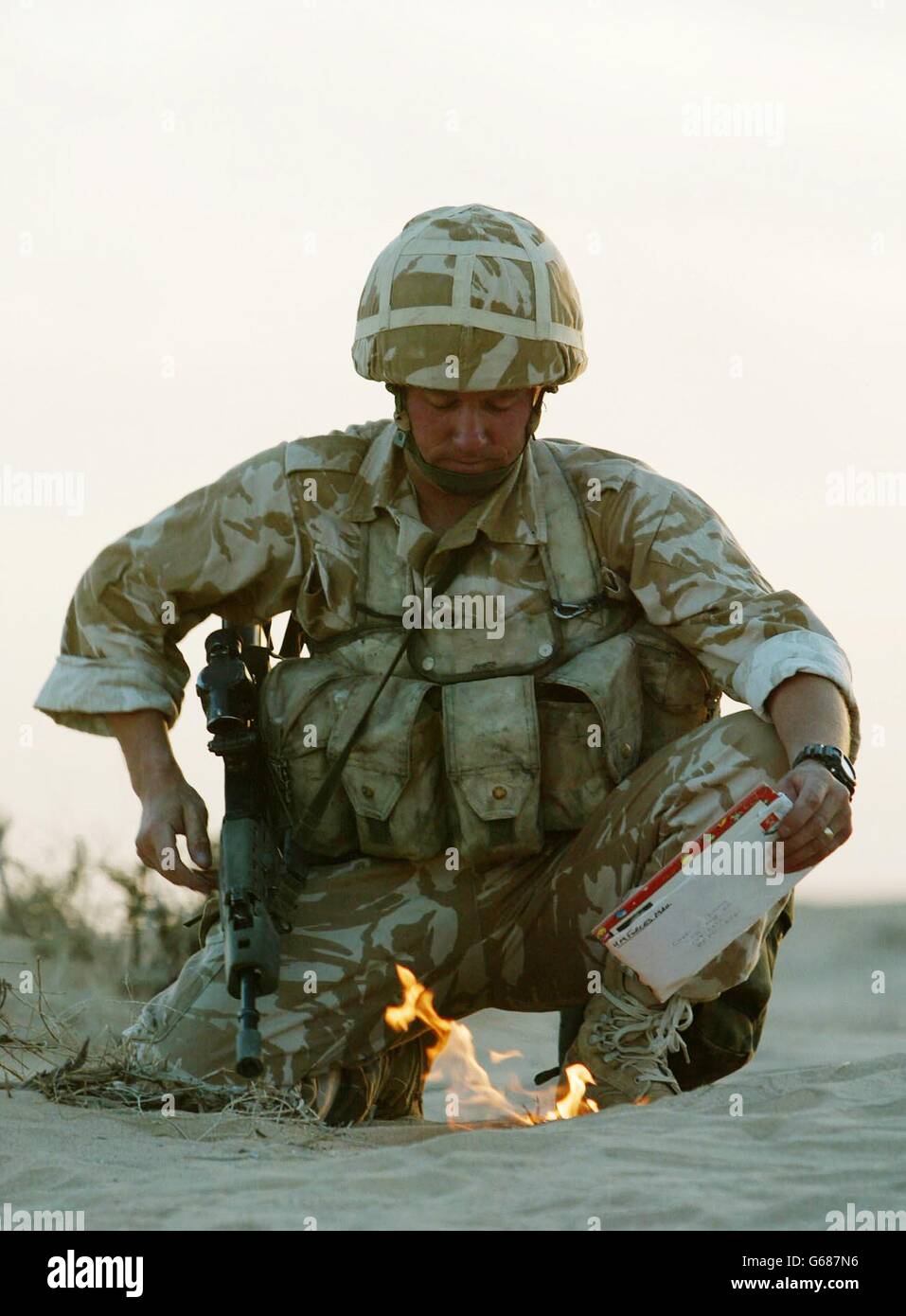 A soldier from the British 29 Commando Regiment Royal Artillery 'sanitises' his kit by burning his personal mail in the Kuwait desert near the Iraqi border. *..Troops potentially involved in future operations sanitise their kit so as not to include any effects that may be of assistance to the enemy. As Military forces in the Gulf gear up for war, U.S. President Bush will meet the British and Spanish Prime Ministers on Sunday amid diplomatic deadlock at the United Nations over U.S.-led plans to disarm Iraq. Stock Photo