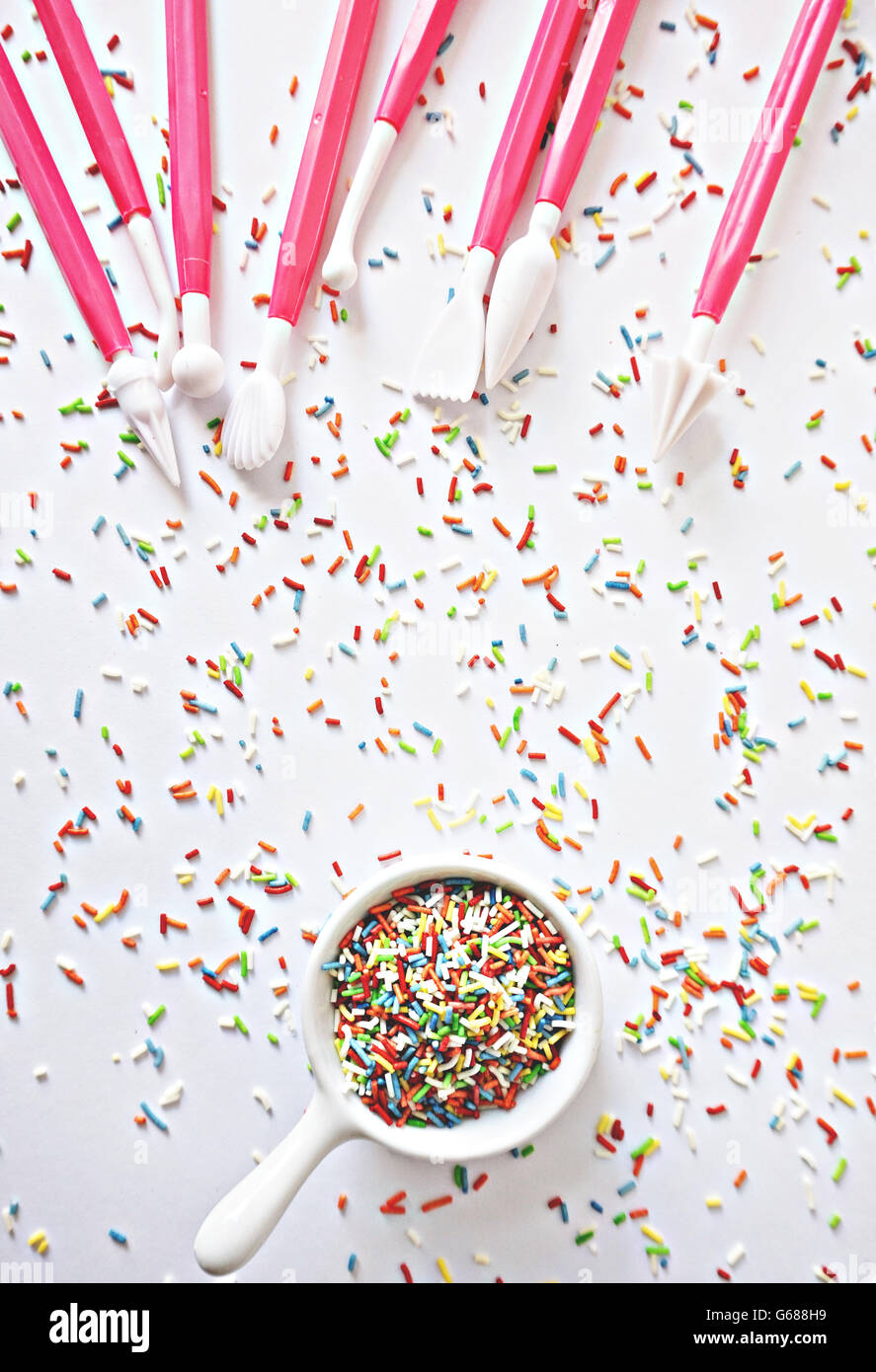 Cenital of sprinkles and cake's decoration tools in a white background Stock Photo