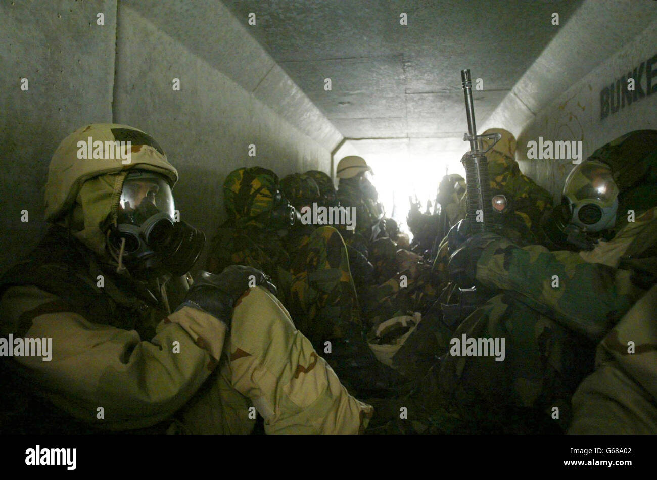 U.S. troops wait in full nuclear biological and chemical protection suits in a bunker at their base in the Kuwait desert after a warning of a second scud missile attack from Iraq. * Iraq fired missiles at Kuwait, prompting U.S. troops to don chemical protective suits and setting emergency air raid sirens blaring in Kuwait City. Stock Photo