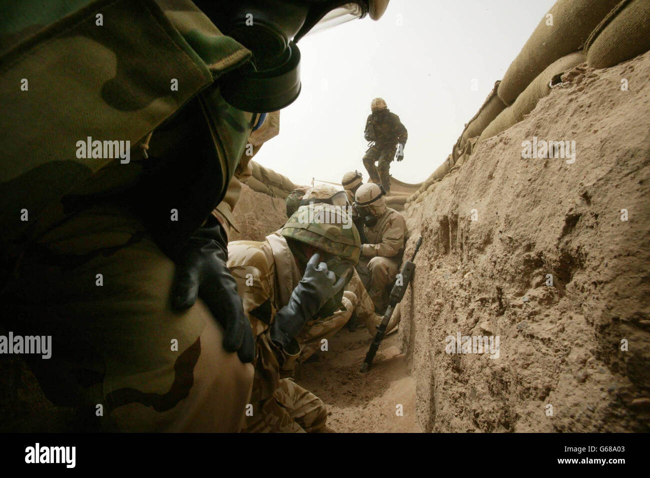 American and British troops take shelter in 'scud trenches' during an unconfirmed Iraqi missile attack in the Kuwaiti desert. The attack came after American forces launched air attacks against Iraq in the early hours of this morning. Photo by Dan Chung, The Guardian, MOD Pool Stock Photo