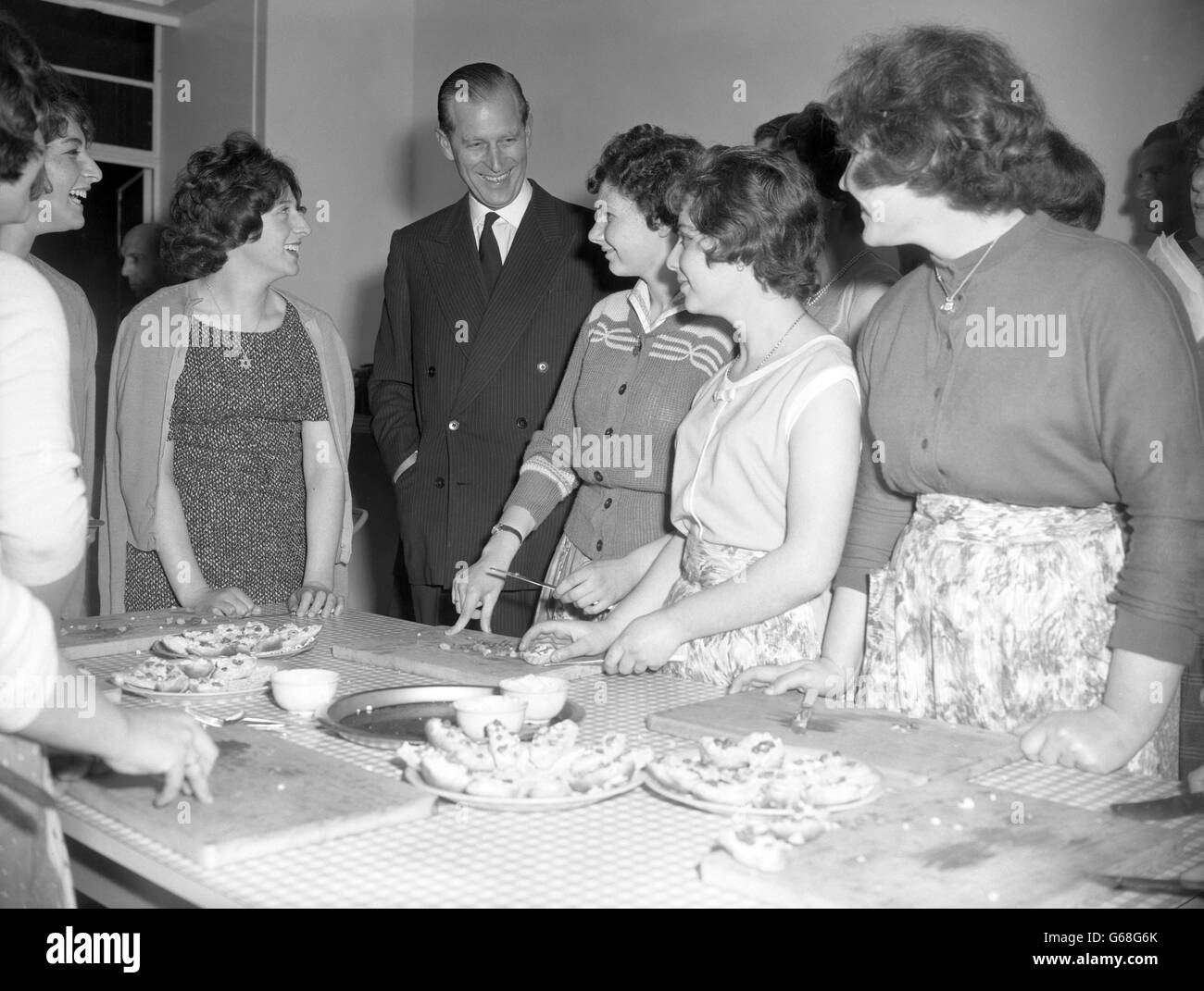 Prince Philip, The Duke of Edinburg looks in on a cookery class in the girl's club during his visit to the Brady youth clubs in Hanbury Street, Stepney, London. The Duke, who is Patron of the London Federation of Boy's Clubs, watched many of the activities during his tour of the boys' and girls' clubs. Stock Photo