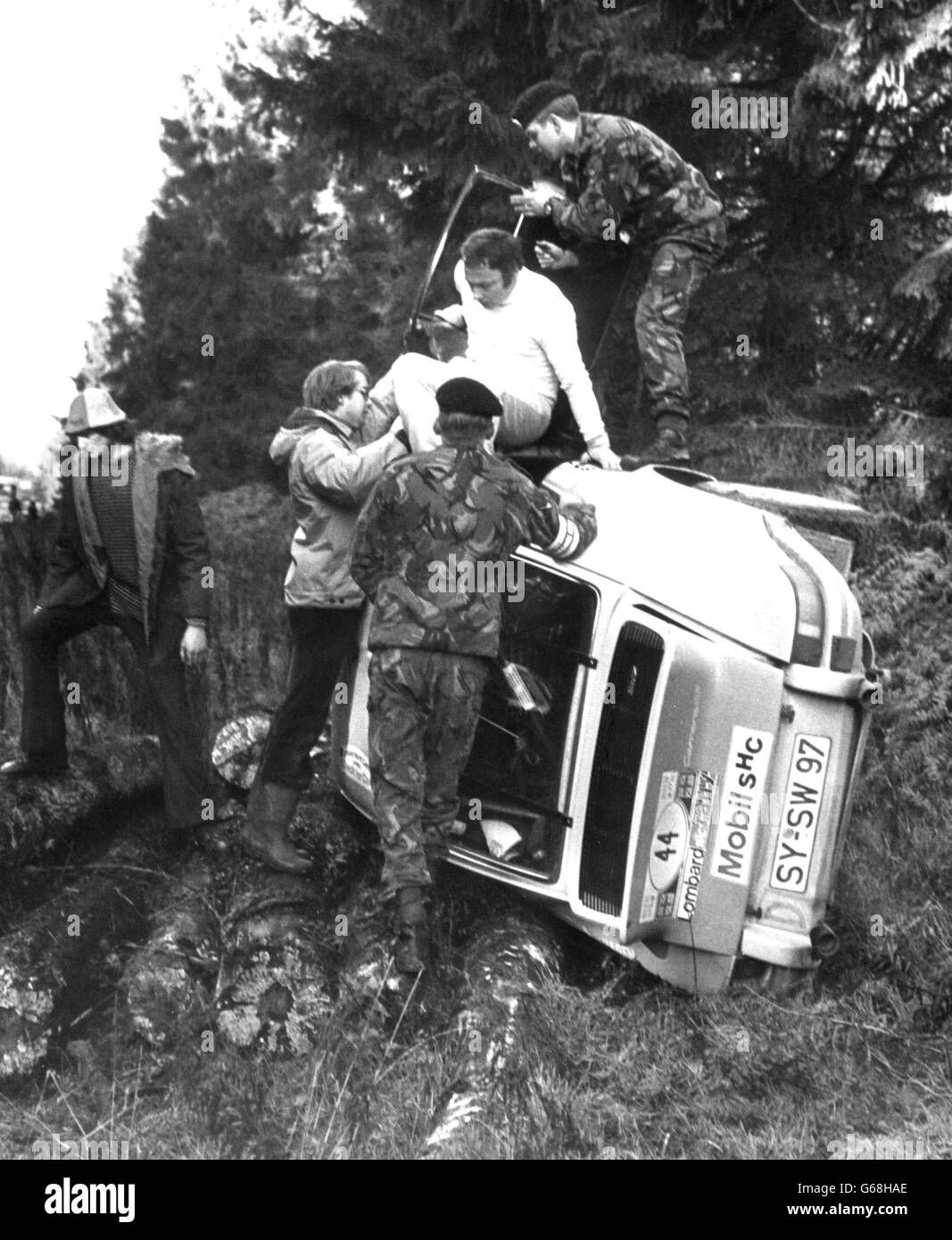 Rally drivers abandon their crashed their Porsche 911SC on a tight bend in the Forest of Dean during the Second stage of the RAC Round-Britain rally. The car was driven by West German driver Heinz-Walter Schewe and his co-driver Franz-Josef Moormann, who escaped with no injuries. Two spectators were seriously injured and several others hurt, causing the stage to be abandoned and competitors moved on to Stage three. Stock Photo