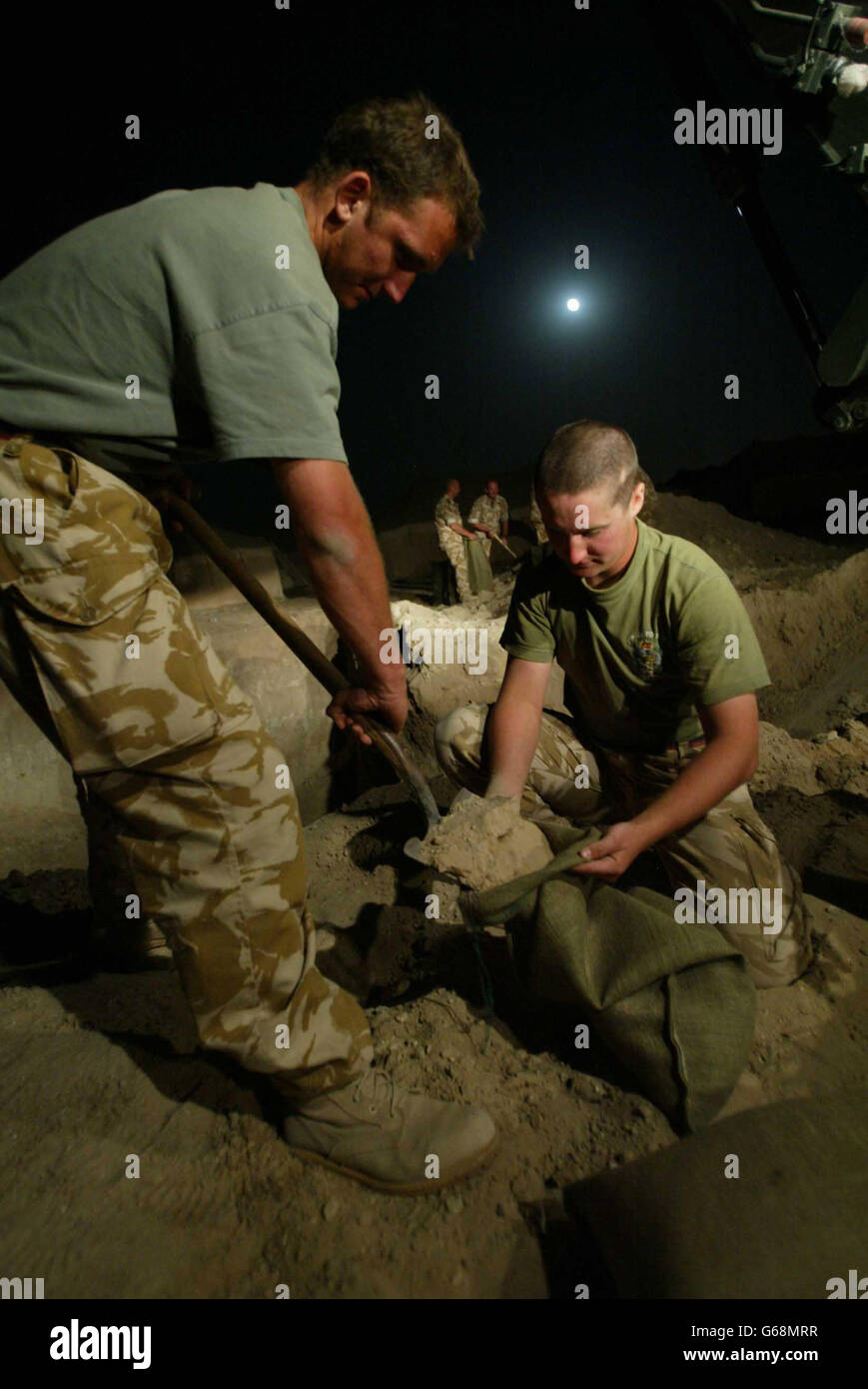 With the moonlight to help them men of the Royal Engineers fill sandbags in the early hours of British time, to pile around bunkers designed to protect British forces from a rocket attack. Stock Photo