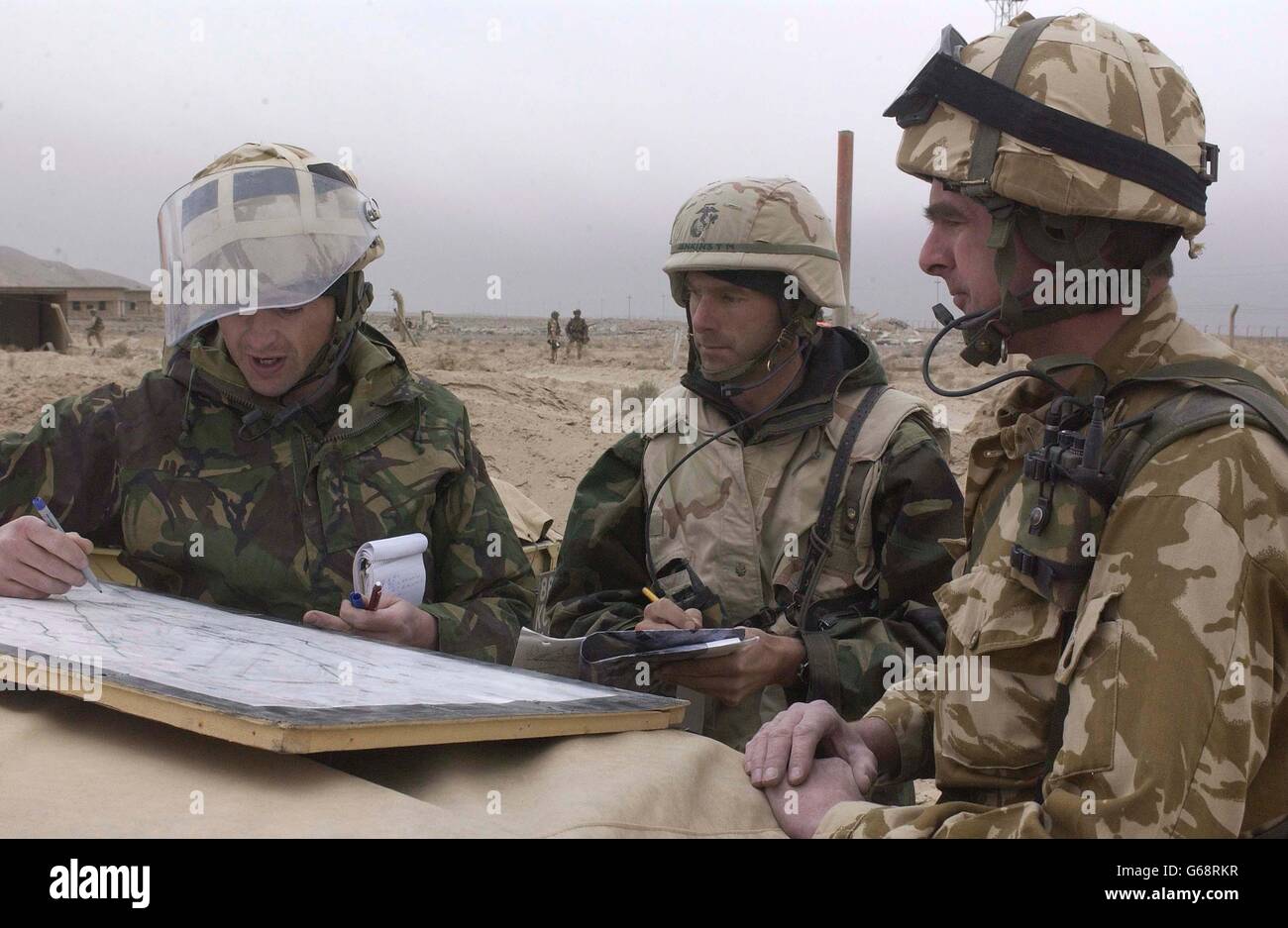 (l/r) Flight Leautenant Chris Long, of 5131 Bomb Disposal Squadron, based at RAF Wittering, briefs his American counterpart as well as Wing Commander Mark Driver, OC 4 Tac STO (Tactical Survive-to-Operate) Squadron, about the risks of unexploded munitions left behind by coalition bombing. The group are preparing to move further into Iraq, setting up forward operating bases for coalition helicopter operations. Stock Photo