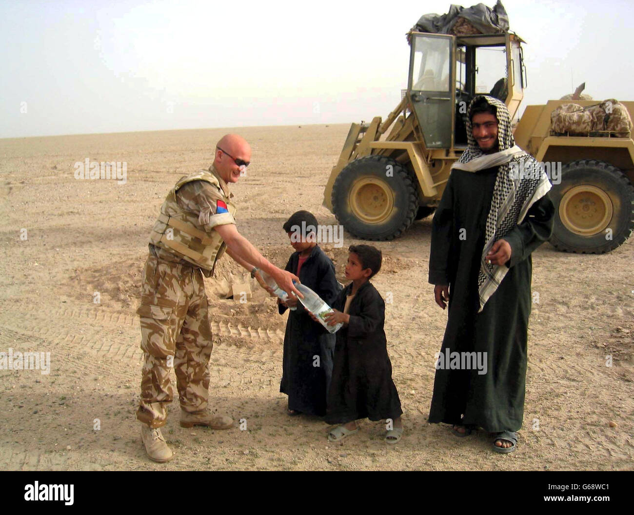 Picture made available of British soldier Sam Chick as he hands out water to a herdsman and his two sons in southern Iraq. Stock Photo