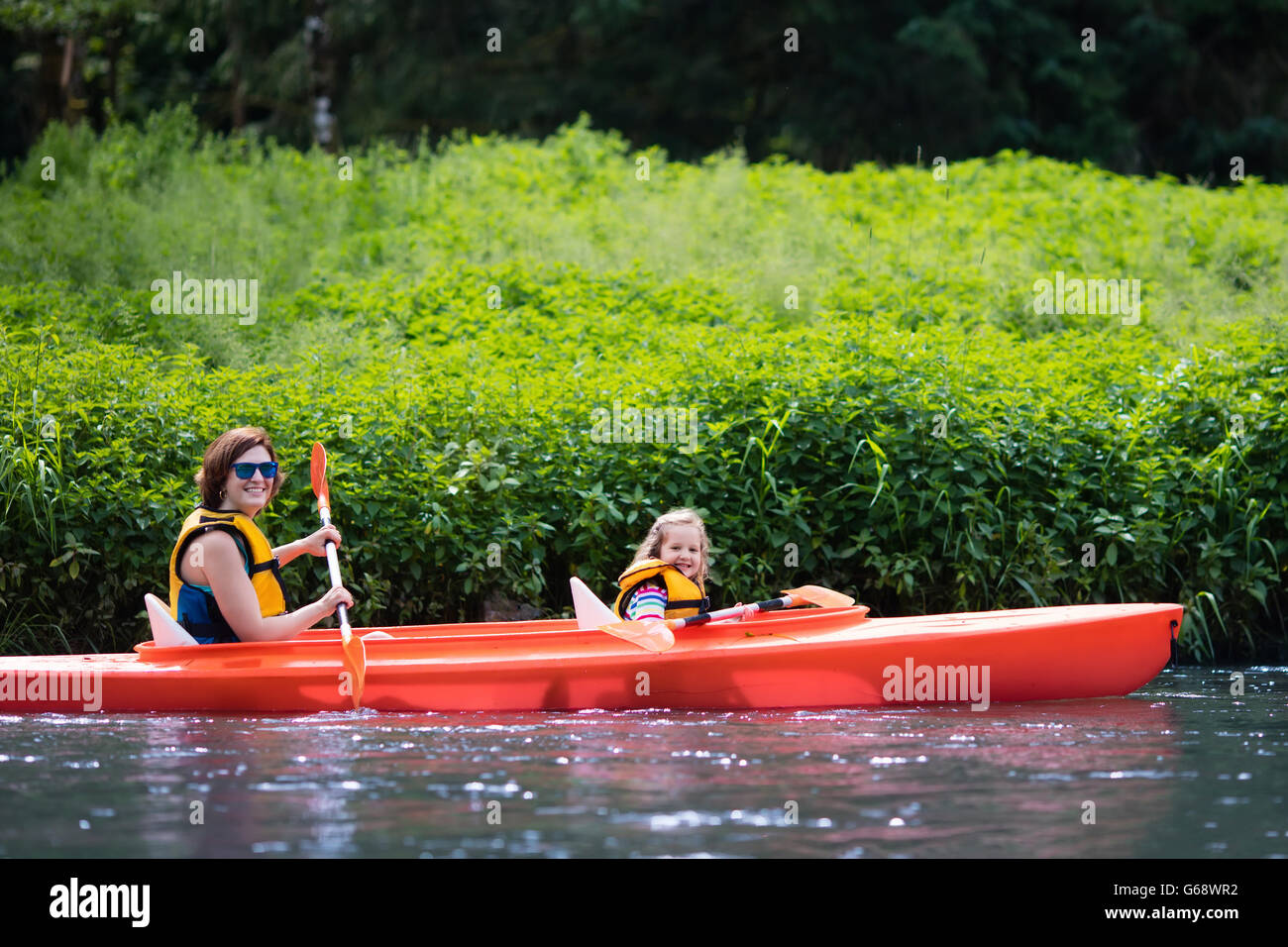 Family on kayaks and canoe tour. Mother and child paddling in kayak in