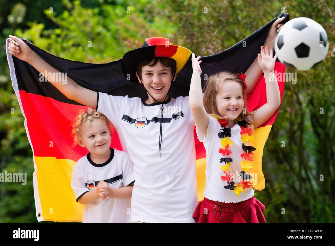 Children cheering and supporting German national football team. Kids fans and supporters of Germany during soccer championship Stock Photo