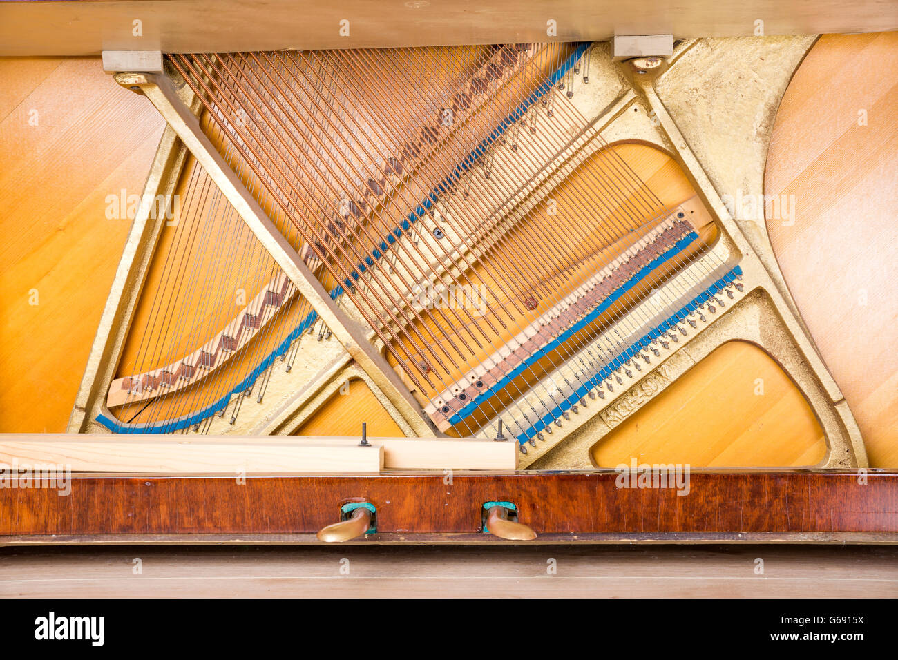 Bottom structure of an upright piano: pedals, metal frame with strings, bass and treble bridges. Stock Photo