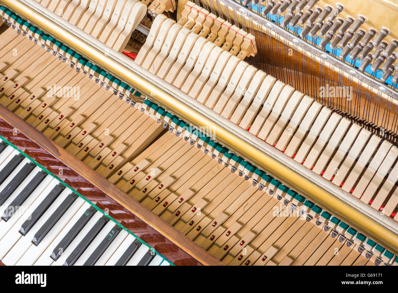 Action mechanics close up inside of an upright piano. Pattern of keys, shanks, hammers and strings. Stock Photo