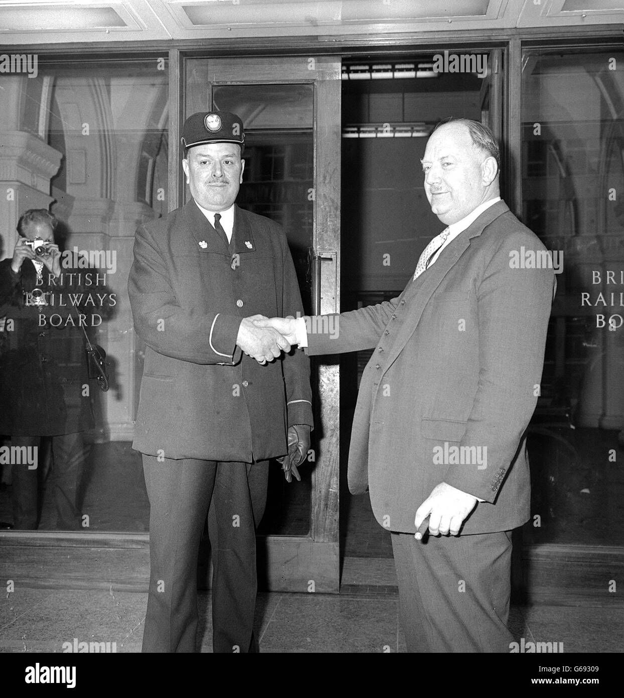 Dr Beeching (right) pictured on the day he left his post of Chairman of the British Transport Commission. He is shaking hands with British Railways commissionaire Mr John Lay, who is wearing a new style uniform. Stock Photo