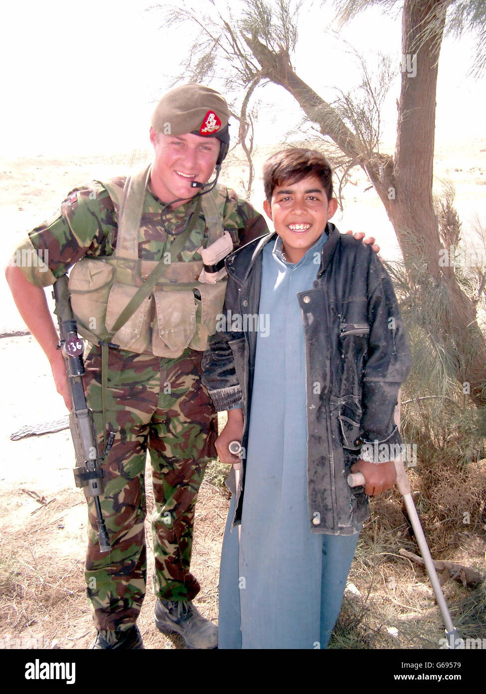 Lance Corporal Nigel Wrigley (Duke of Wellington's Regiment)- without his helmet for the first time since the start of the Iraq campaign - cuddles a boy landmine victim near Safwan, Iraq. Stock Photo