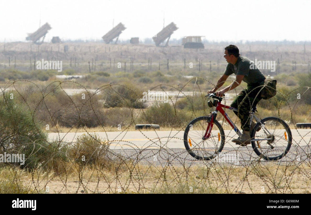 A British Royal Air Force Harrier GR7 groundcrew member cycles along the apron infront of a Patriot Missile defence system on his base in. U.S. troops have a tight control on Baghdad airport and will move out from there in all directions, *..Jim Wilkinson, a spokesman for U.S. commander General Tommy Franks, said. Stock Photo