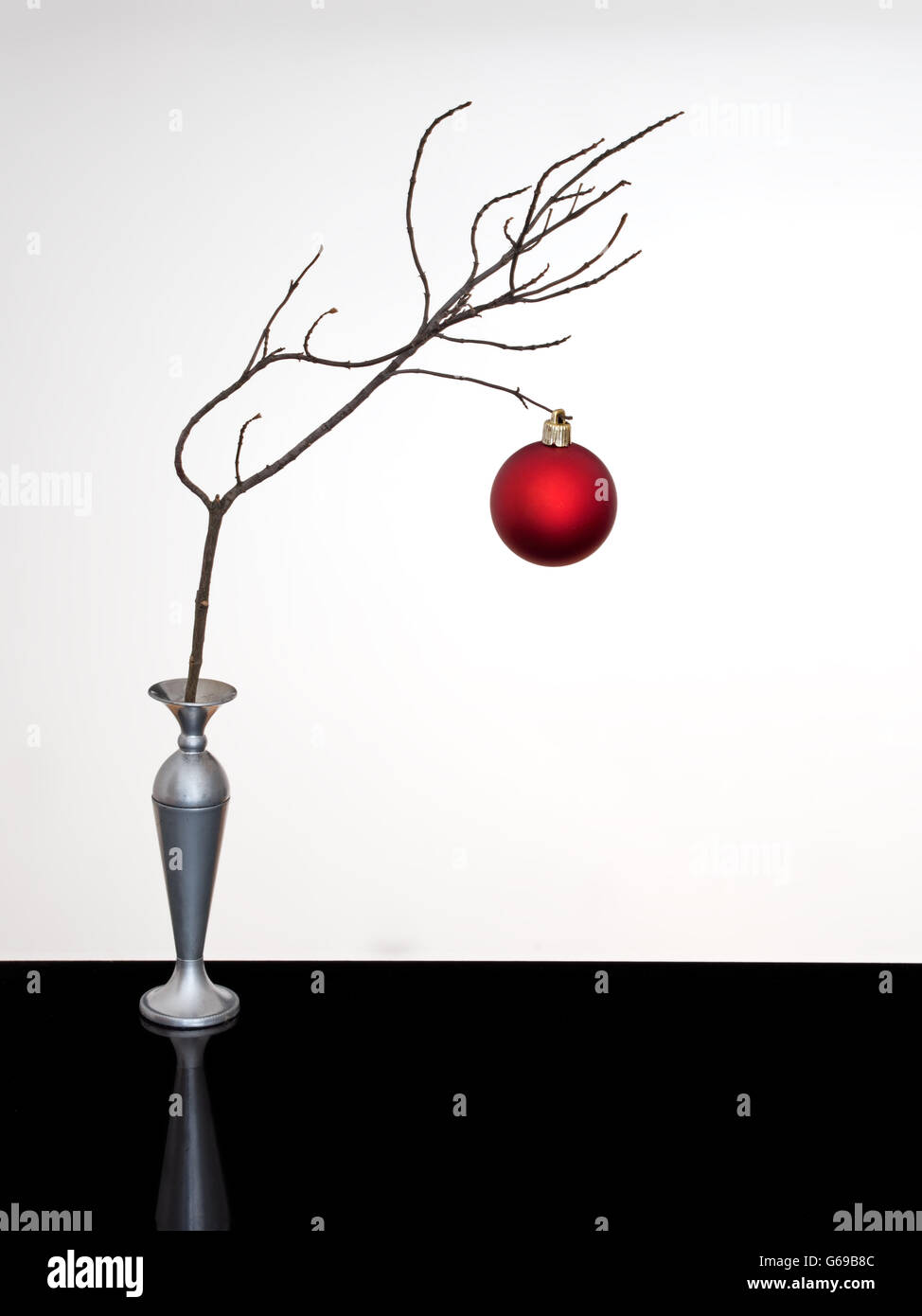 Red bauble.Simple silver festive decoration on black shiny surface. Stock Photo