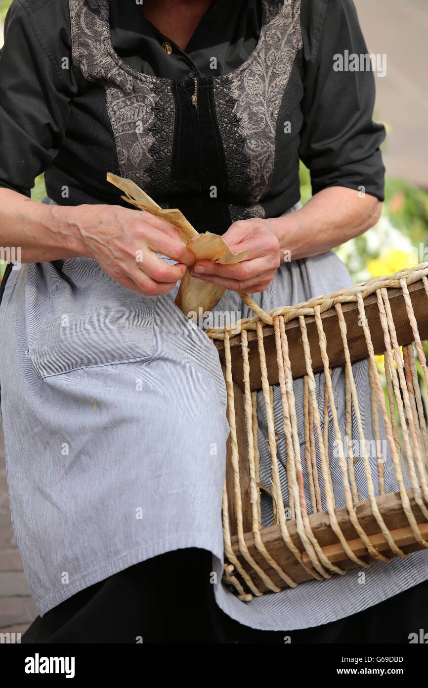 skilled hands of an elderly woman while twist the straw to create a