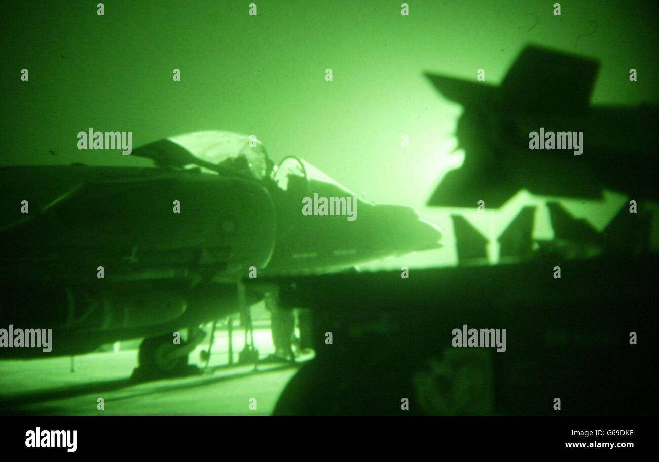 Seen through a night vision scope, a British Royal Air Force pilot sits in his Harrier GR7 behind bombs as ground crew go through final checks in their base in Kuwait before his mission over Iraq . * U.S. and British troops moved into forward positions on Wednesday, ready to unleash a massive assault on Iraq as time ticked away for President Saddam Hussein to avoid war by choosing exile. Stock Photo