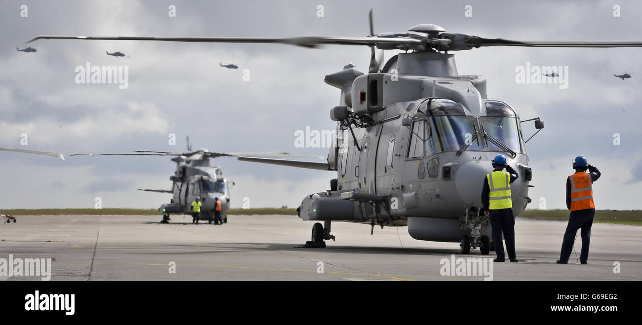 Helicopters fly over Merlin Mk 2 aircraft at Royal Naval Air Station Culdrose, Cornwall, where the first of the UK's fleet of next generation anti-submarine maritime patrol Merlin helicopters have been handed over to the Royal Navy. Stock Photo