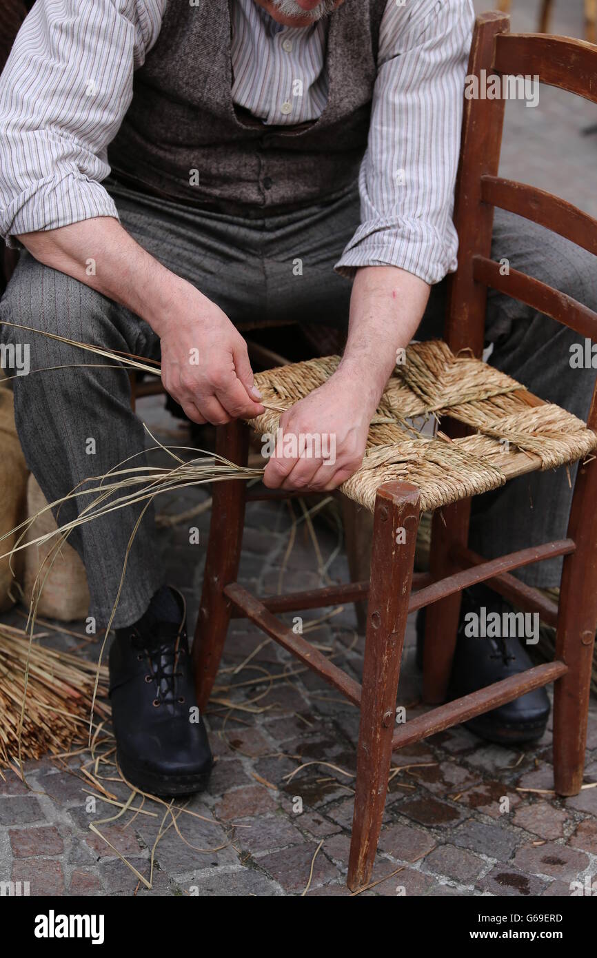 old man mender of chairs while repairing old wooden chair Stock Photo