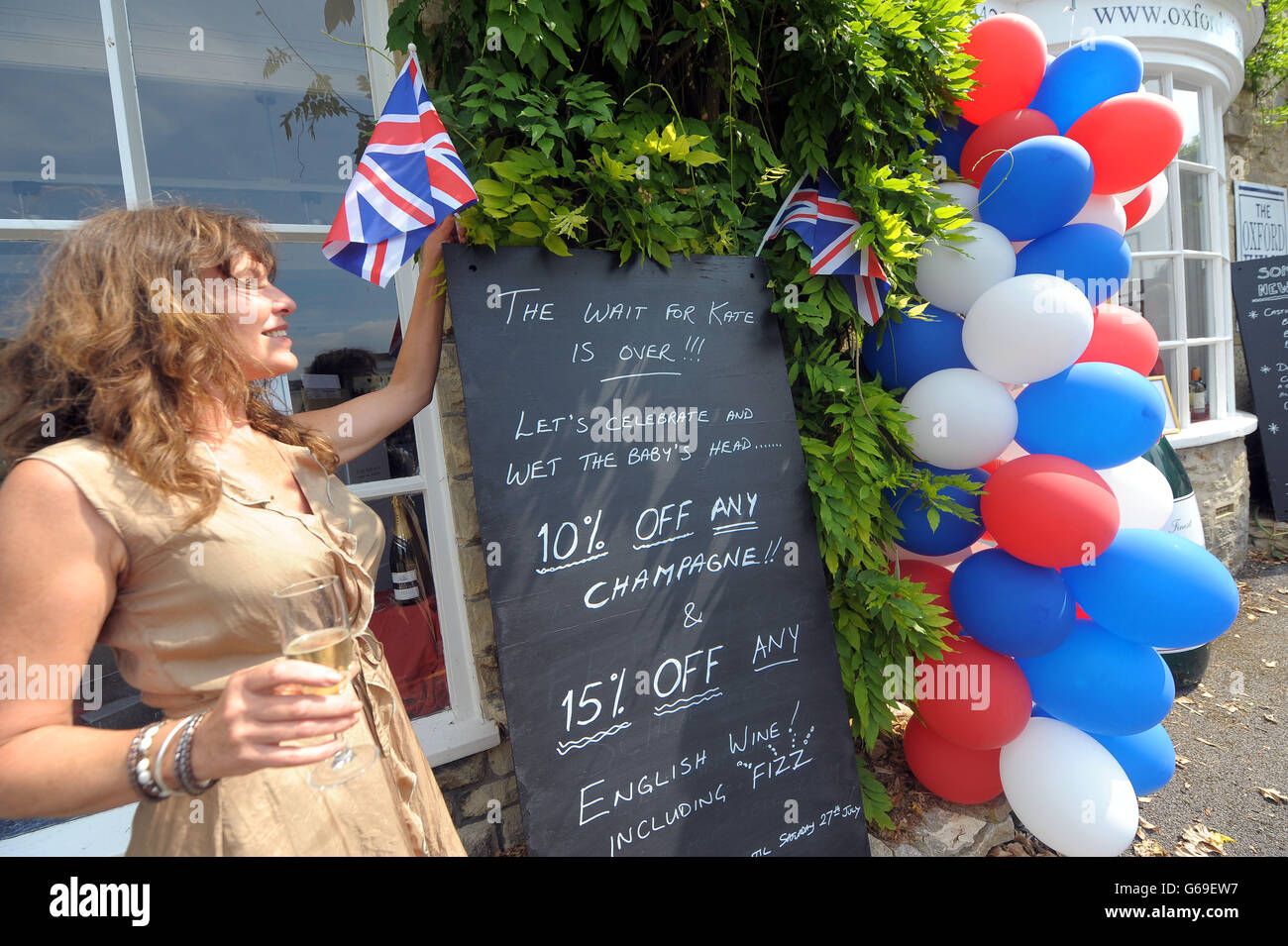 Uma Wylde with the display outside the Oxford Wine Company shop celebrating the birth of the Royal baby in Tetbury, Gloucestershire, celebrating the birth of the royal baby. Stock Photo