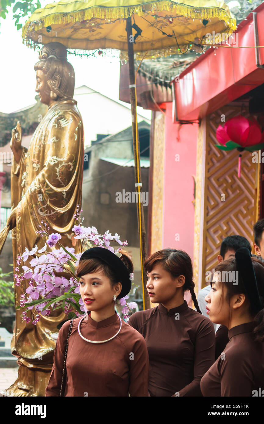 Vietnamese Girls in Ao Dai stand in front of Guanyin statue Stock Photo