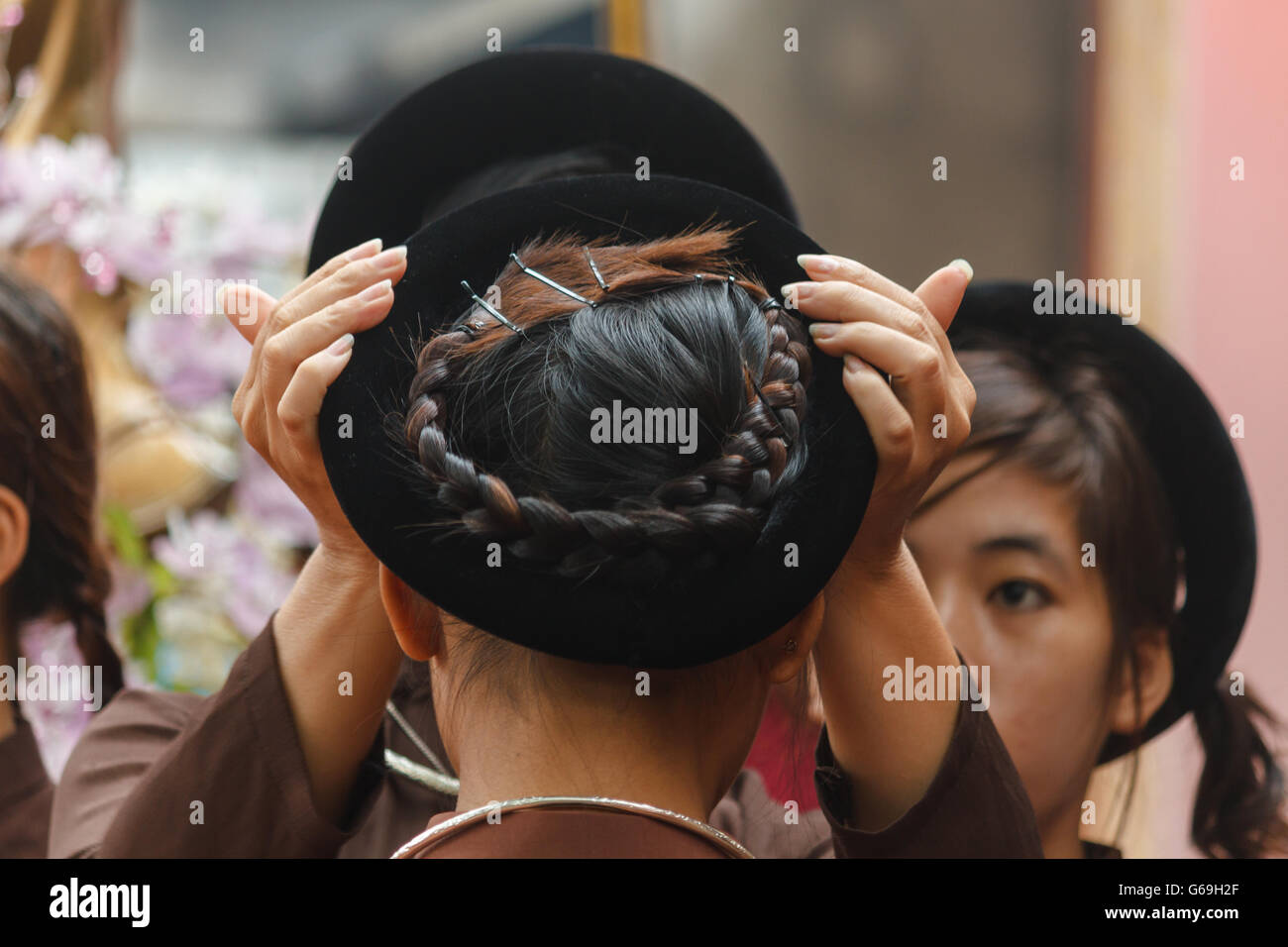 Woman in Ao Dai prepares girls for religious ceremony in Central Vietnam Stock Photo