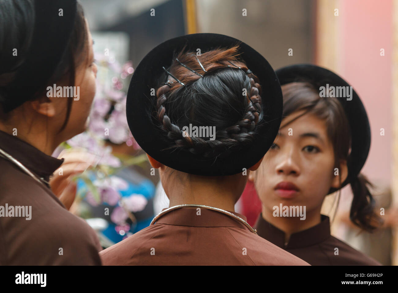 Woman in Ao Dai prepares girls for religious ceremony in Central Vietnam Stock Photo