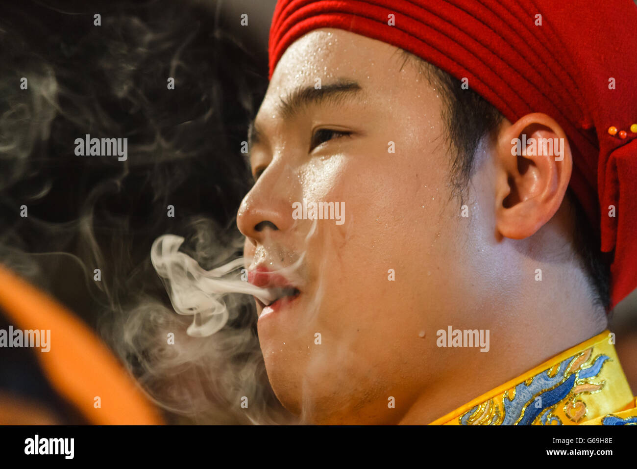 Male Medium smokes while preparing for spirit mediumship ritual in Vietnam Stock Photo
