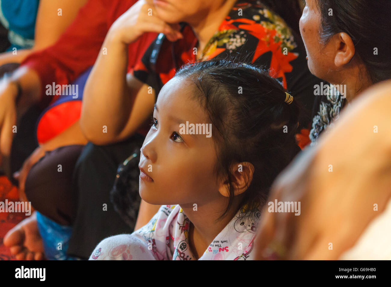 Young Vietnamese girl watching a religious ceremony Stock Photo