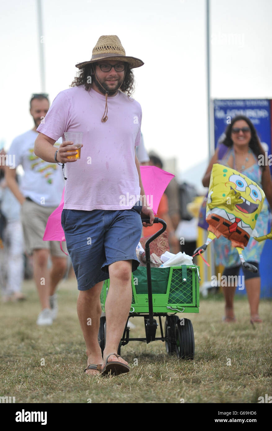 A festival goer runs to shelter from the rain during the Womad Festival 2013, held at Charlton Park, Wiltshire. Stock Photo