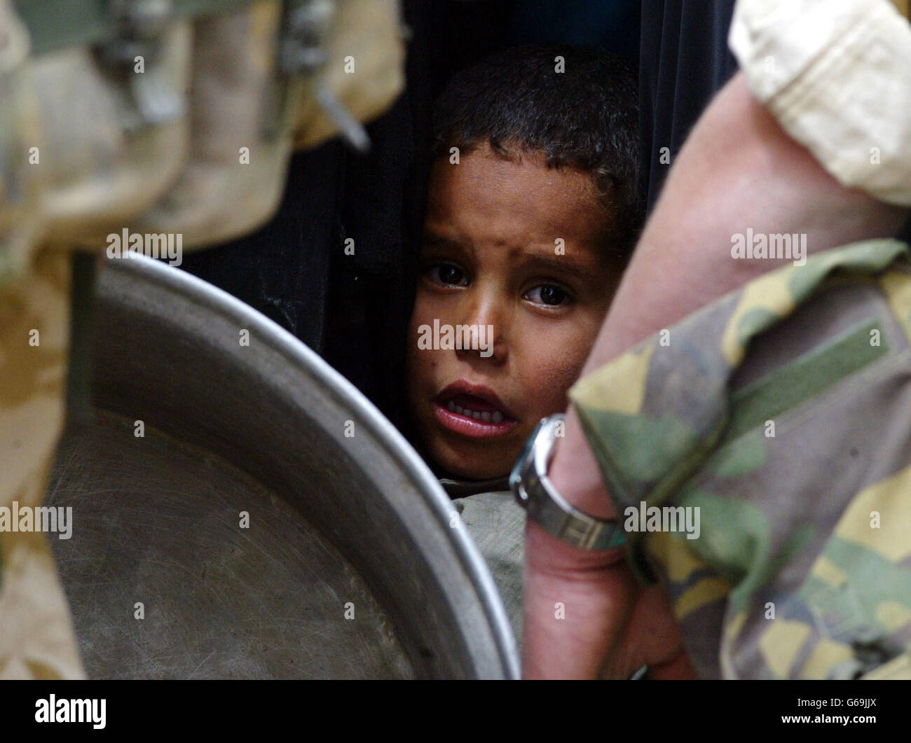 A young Iraqi child waits his turn for water as British soldiers from the 23 Pioneer Regiment hand out fresh water from a tanker in the southern Iraqi town of Safwan. The British forces are helping the local people with humanitarian aid. Stock Photo