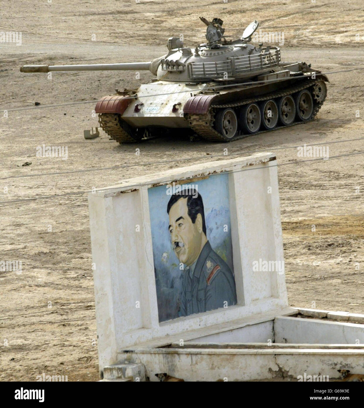 Iraqi T55 tank in Al Qurnah.. A destroyed Iraqi T55 tank, sits in front of a picture of Saddam Hussein south of Al Qurnah. Stock Photo