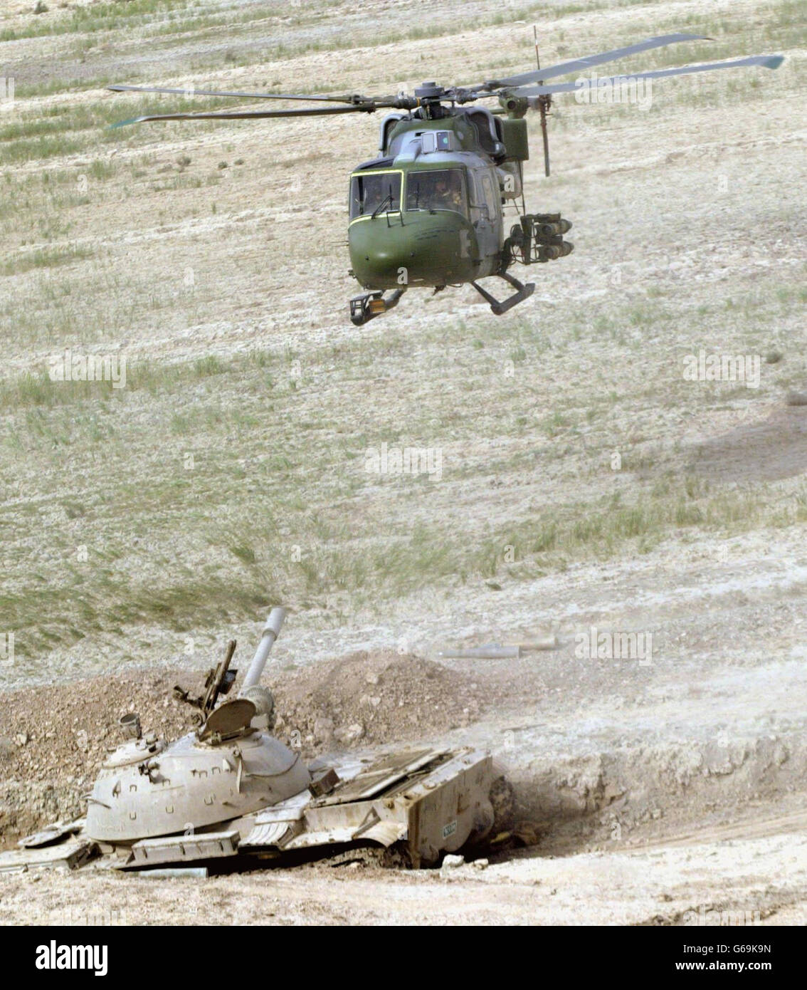 A Mark 7 Lynx helicopter from 3 Reg Army Air Corps, 16 Air Assault Brigade on a combat patrol, carrying TOW missiles, flies over a destroyed Iraqi T55 tank, south of Al Qurnah. Stock Photo