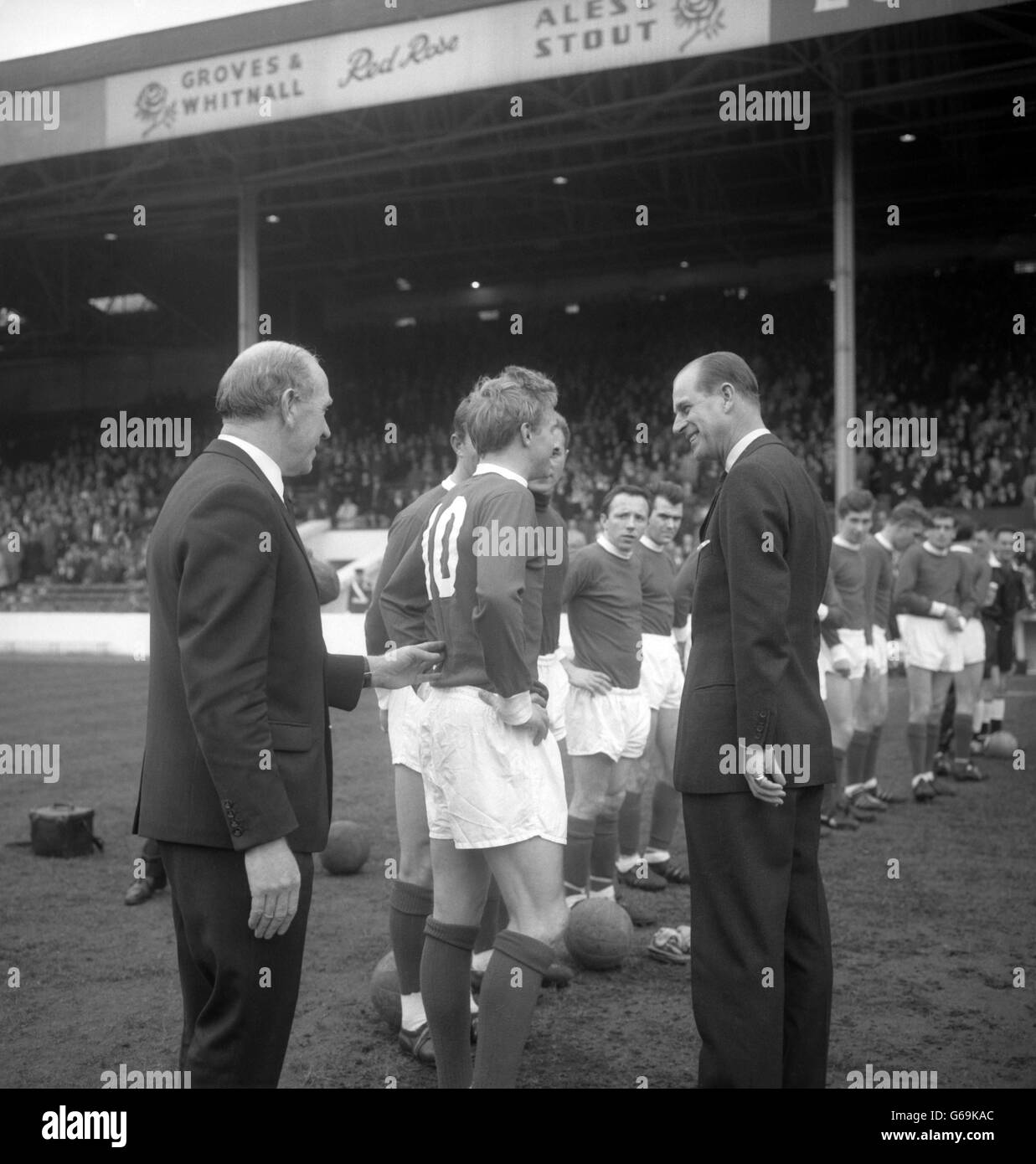 Manchester United's Denis Law gets a prod forward from manager Matt Busby as he is introduced to Prince Philip, The Duke of Edinburgh, during the team line-up before the match Stock Photo
