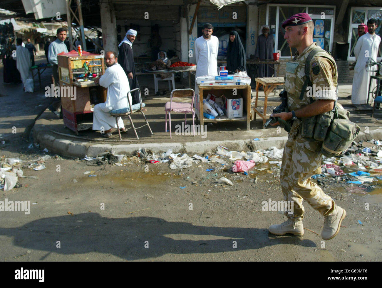 A soldier from C company of the 1st Battalion The Parachute Regiment casts a long shadow as he passes traders in the market of Al Qurna, Iraq. He and colleagues from seven platoon patroled on foot near the biblical Garden of Eden wearing berets and not helmets for the first time. Stock Photo