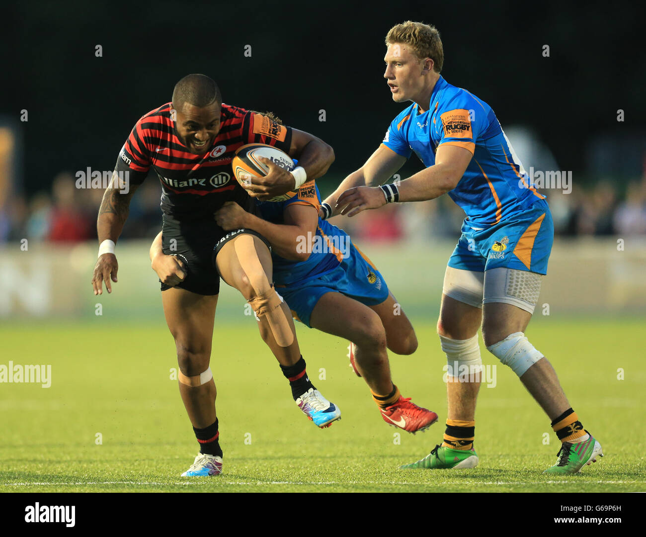 Saracens' Michael Tagicakibau is held by Wasps' Tom Howe during Group C match of the J.P. Morgan Asset Management Premiership Rugby 7's match at Allianz Park, London. Stock Photo