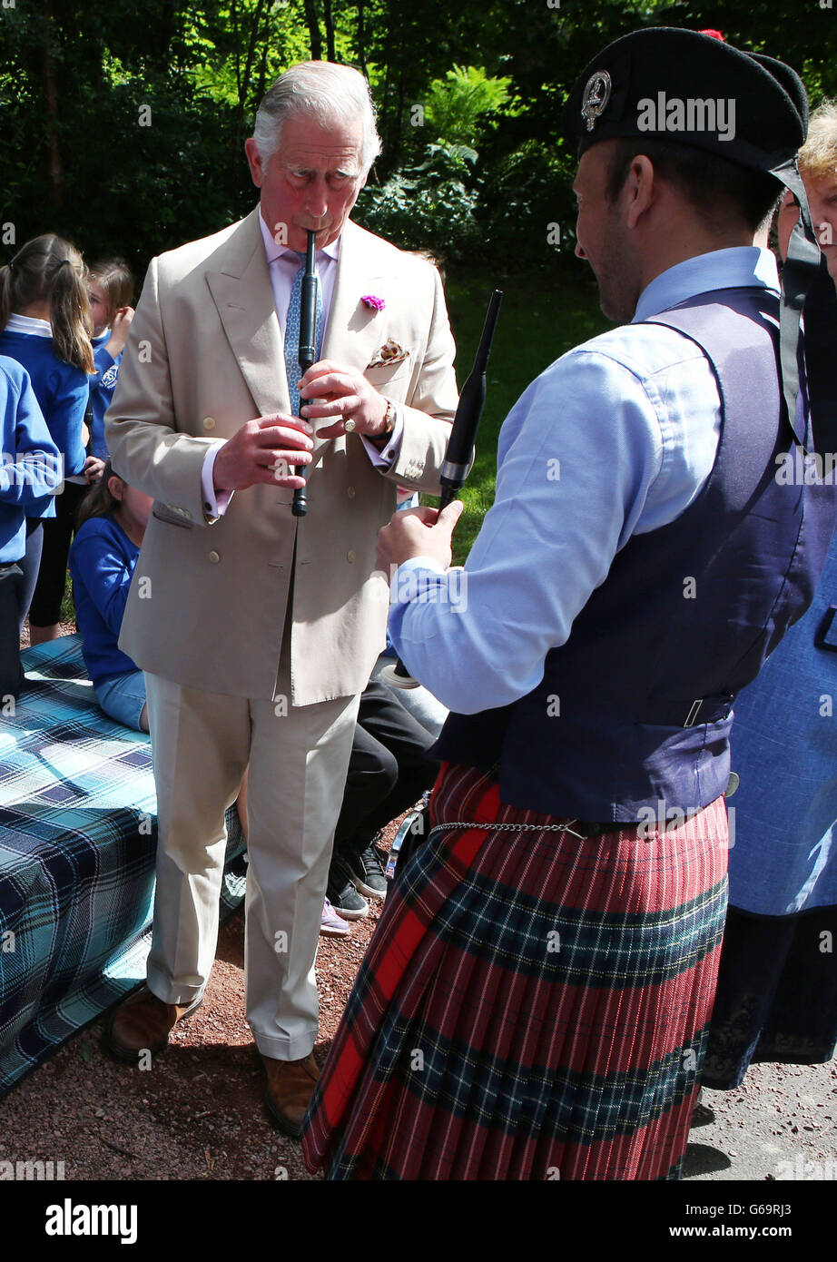 The Prince of Wales, known as the Duke of Rothesay while in Scotland, plays a chanter as he takes part in chanter lesson with local school children taught by Alisdair McLaren during his visit to the National Piping Centre at the Dumfries House Estate in Cumnock as it holds a 'Come and Try' workshop. Stock Photo