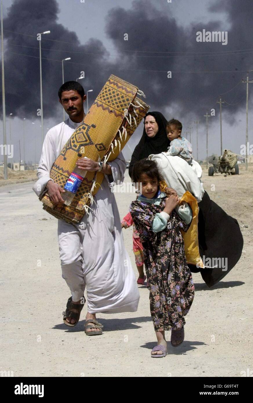 Locals flee the burning town of Basra in Iraq. Stock Photo