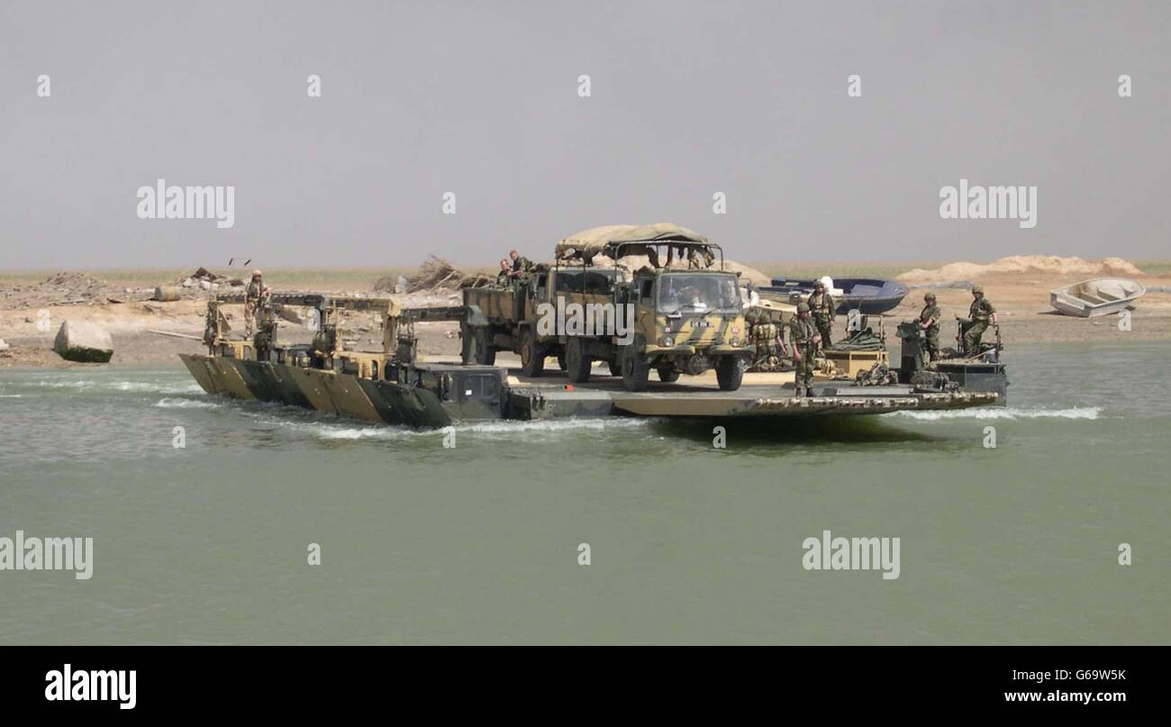 Military vehicles are brought across the Shat Al Basra in southern Iraq, on board the British Army's M3 rigs, which drive on land but convert in to ferries. It is an example of the support the Royal Engineers provide in the war effort. Stock Photo