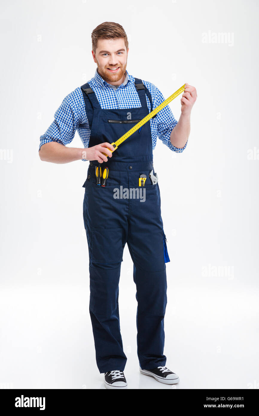Smiling young worker standing and holding masuring tape Stock Photo