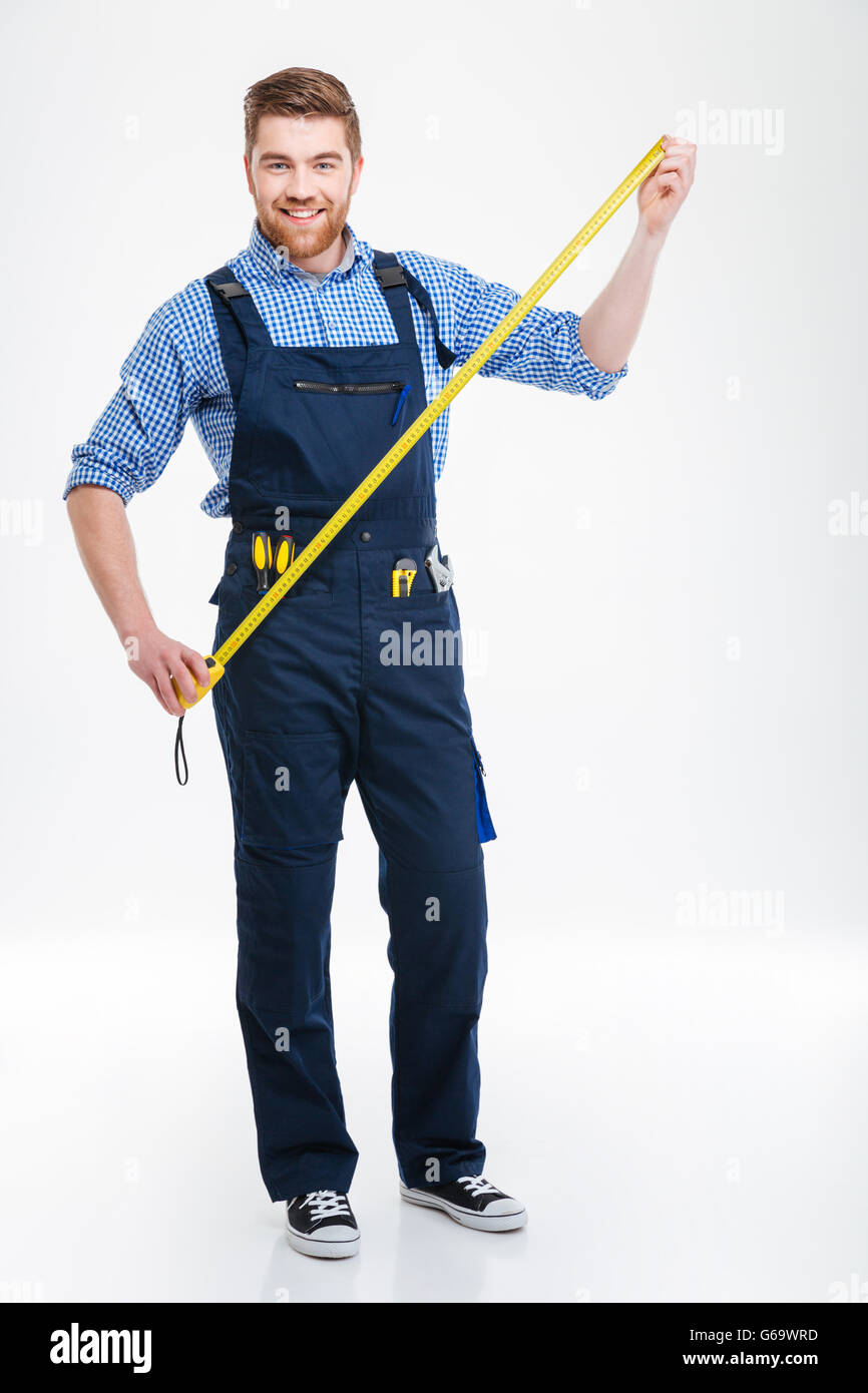 Full length of happy bearded young worker holding masuring tape Stock Photo