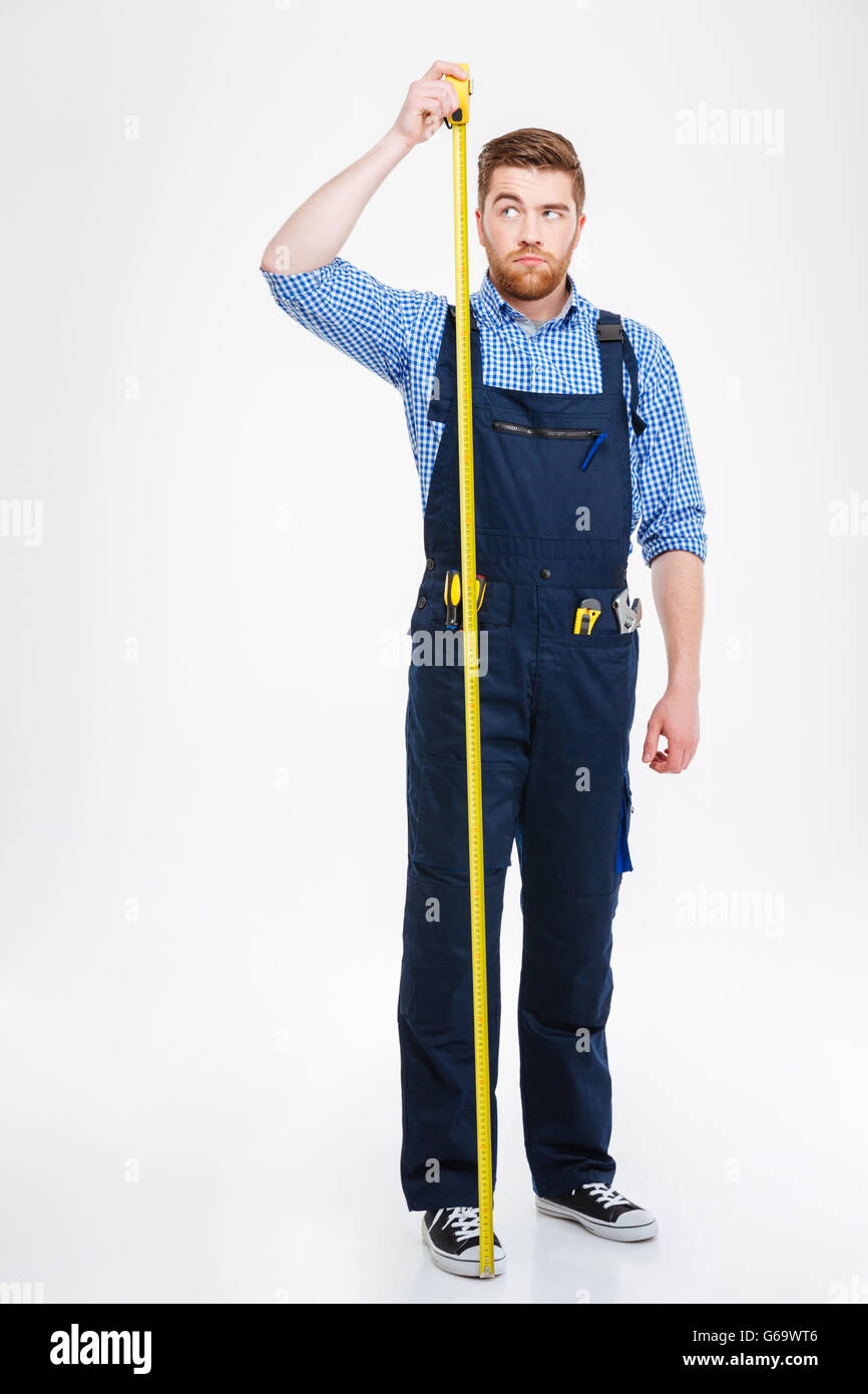 Serious young worker standing and measuring hid growth with yellow tape Stock Photo