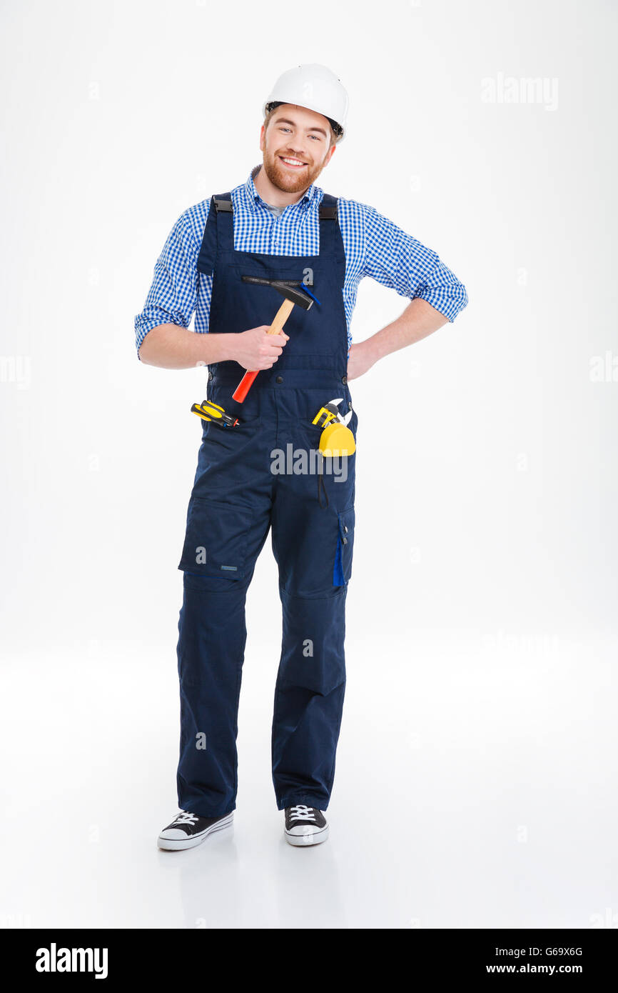 Happy young builder in helmet standing and holding hammer Stock Photo