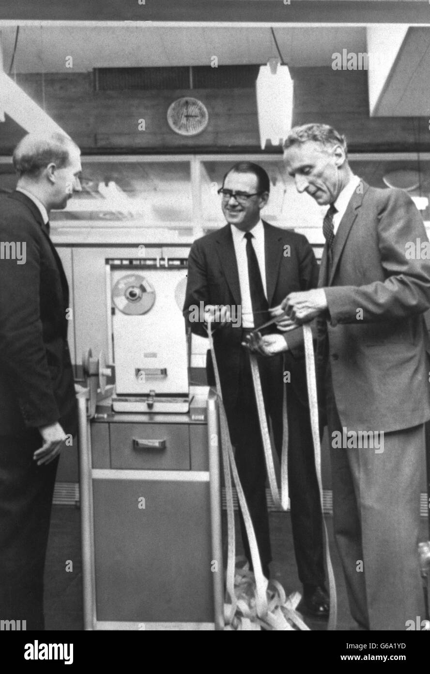 Examining the output of a computer which can give quick answers are (from l-r) Sir Roger Stevens, Vice-Chancellor of Leeds University, Professor Brian Flowers, of Manchester University and Chairman of the Computer Board of Universities, and Professor G.B. Cook, Director of Leeds University. Professor Flowers is examining the output of a paper punch, part of the K.D.F. 9 Computer at Leeds University, which is able to do more work after a recent upgrade with new equipment. Stock Photo