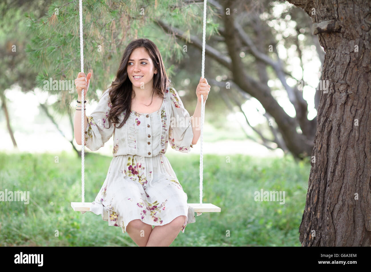 Smiling Woman Sitting on a Swing in a Park Stock Photo - Alamy